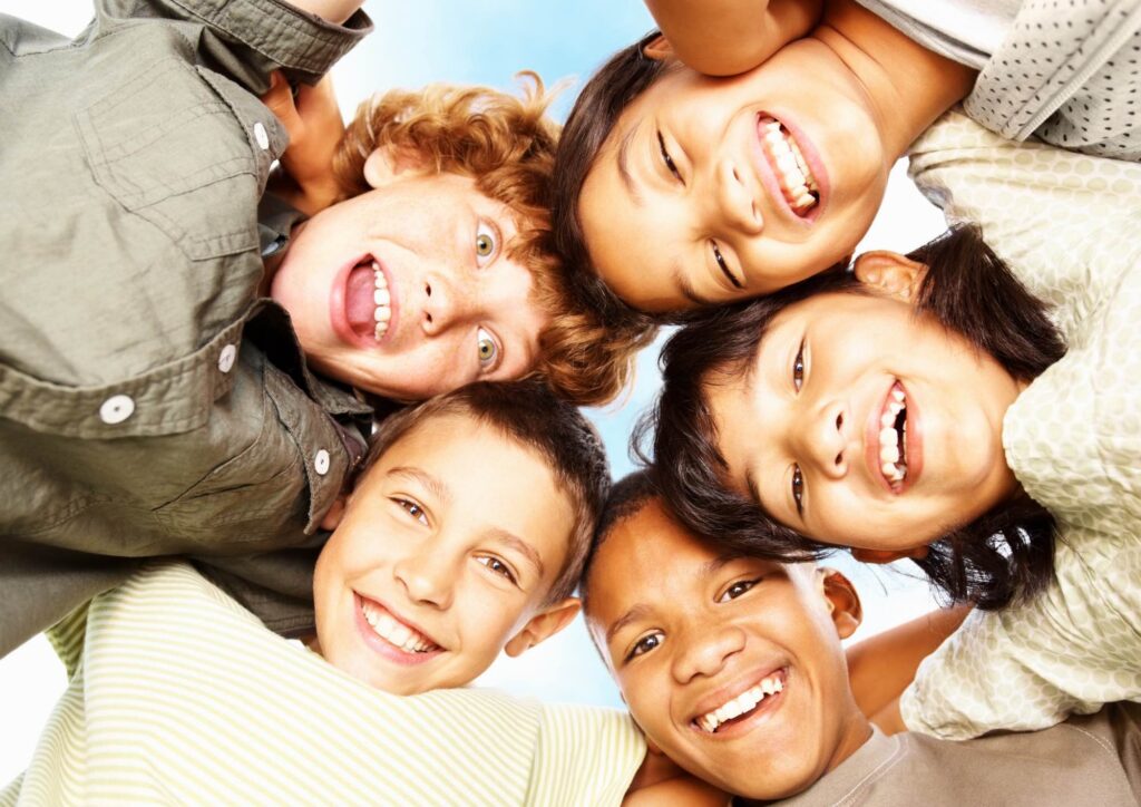 Groupe d'enfants souriants réunis en cercle, vus d'en bas